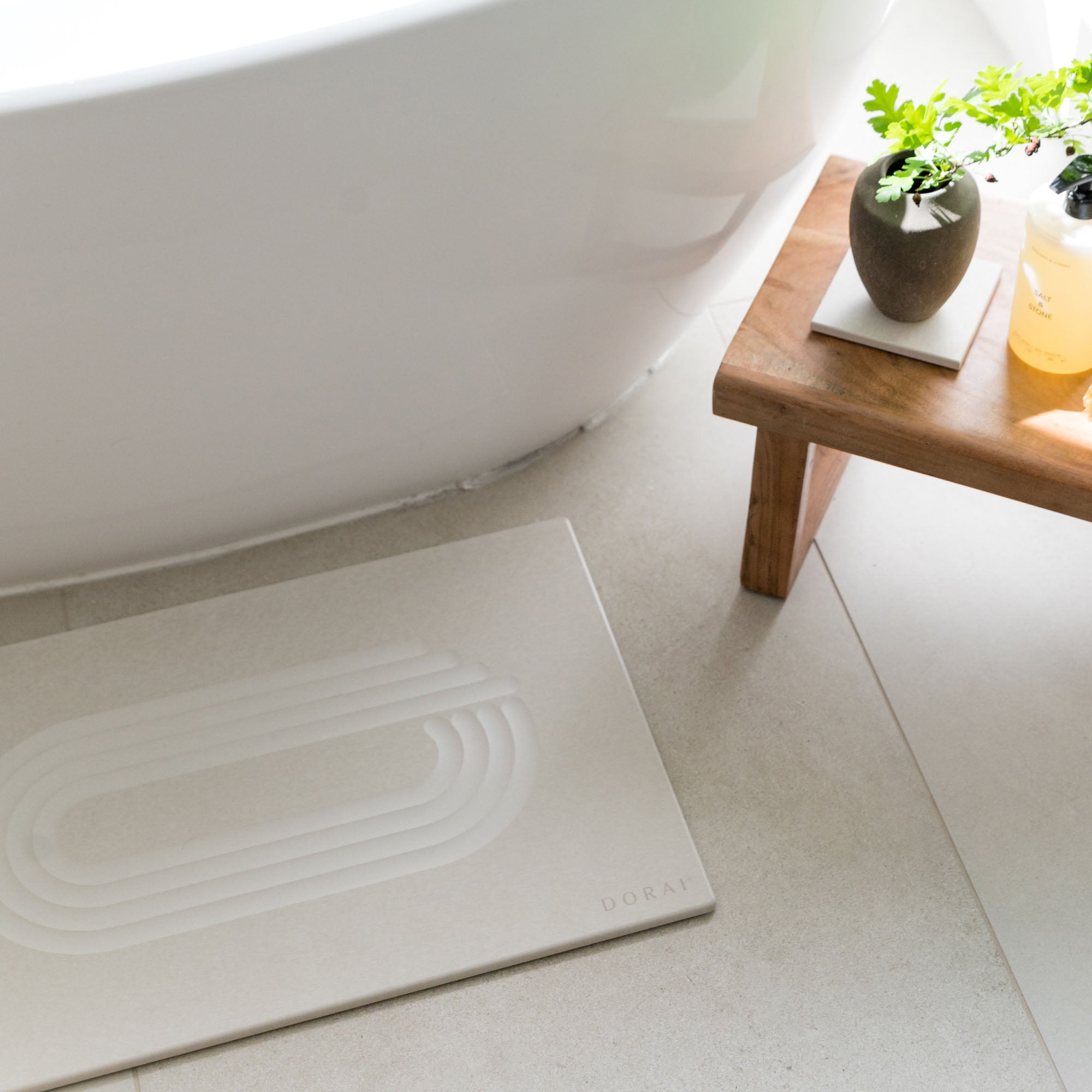 Dorai Current Bath Stone in sandstone beside a freestanding tub