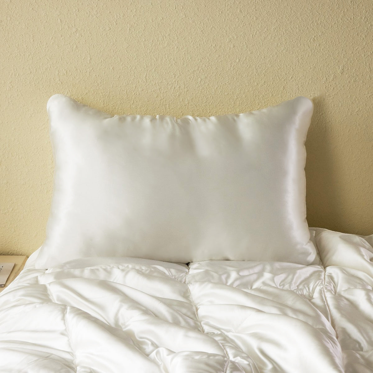 White Promeed silk pillowcase arranged with coordinating silk bedding