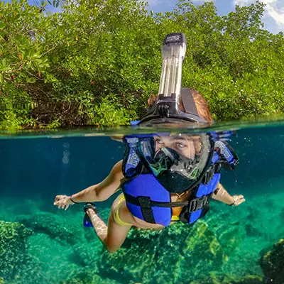 Visitor snorkeling in a clear turquoise inlet at Xel-Ha Park